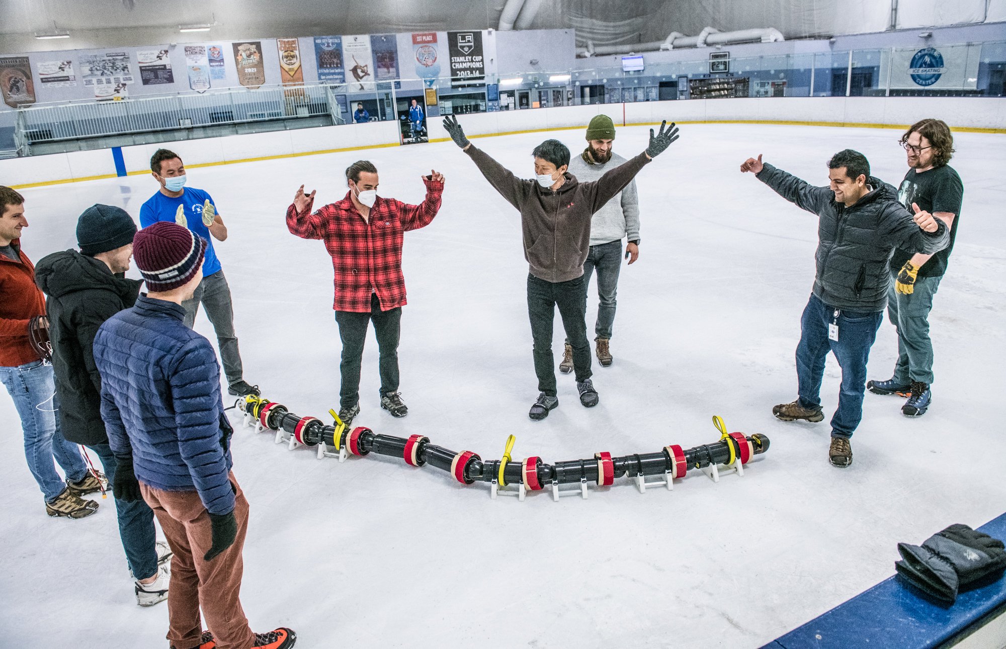 Members of JPL’s EELS team celebrate the robot’s first field test at an ice rink in Pasadena, California, in July 2022. Principal investigator Hiro Ono is just right of center, in the brown sweatshirt. Credit NASA/JPL-Caltech.