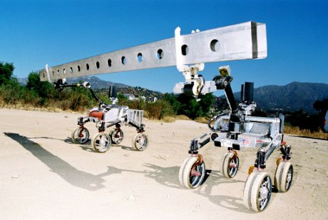 Fig. 1: SRR and SRR2K acting as the Robot Work Crew, transporting an extended beam (2.5 meters long) in the Arroyo Seco next to JPL. The terrain is sandy soil with an average slope of 9-degrees.